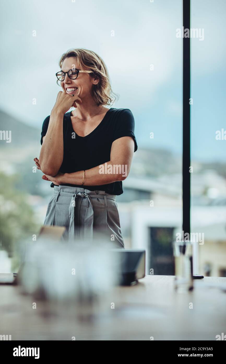 Geschäftsfrau steht am Konferenztisch und lächelt. Erfolgreiche weibliche Profi im Tagungsraum. Stockfoto