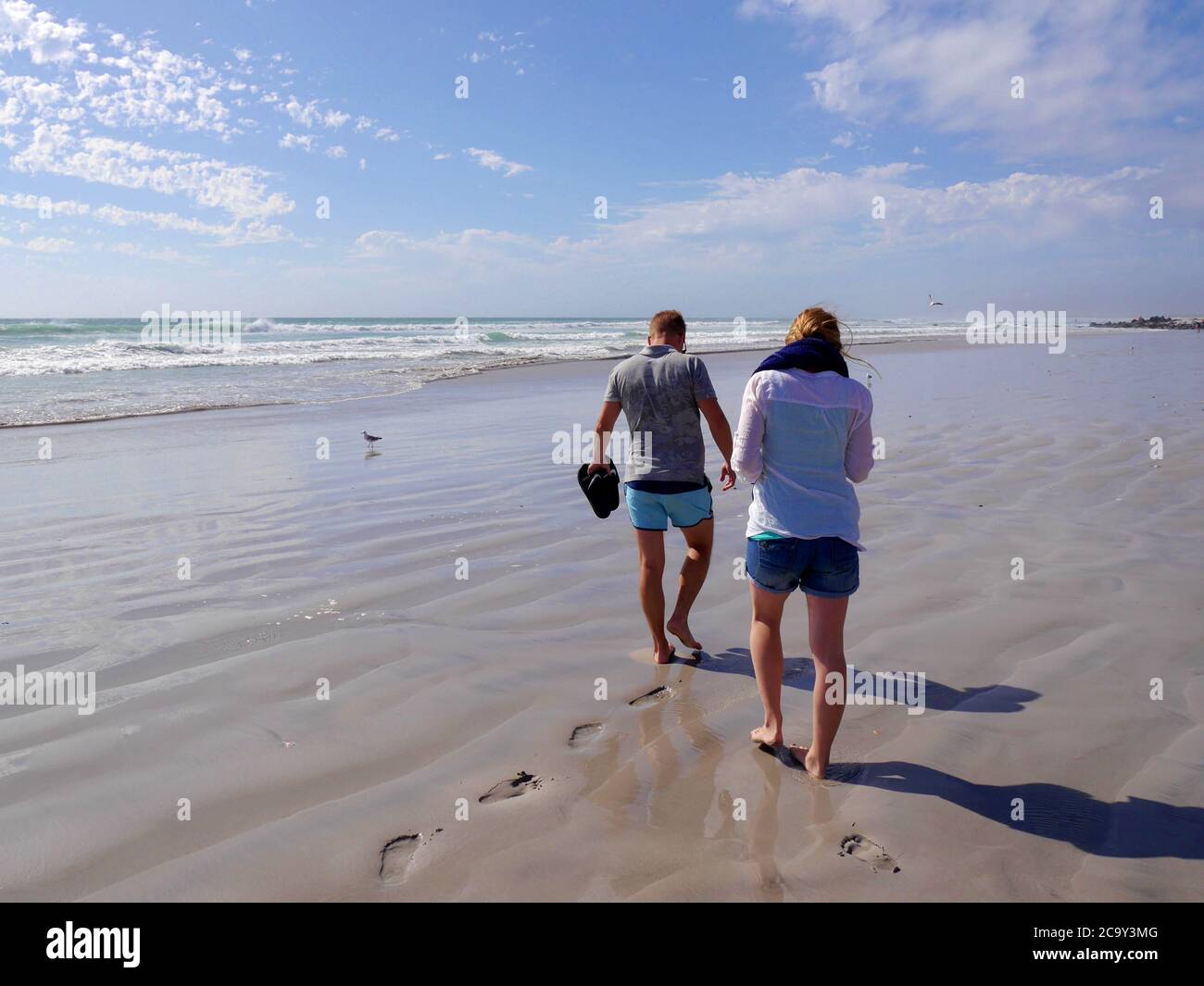 Junges Paar in Sommerkleidung auf menschenleeren, weißen Sandstrand zu Fuß Stockfoto