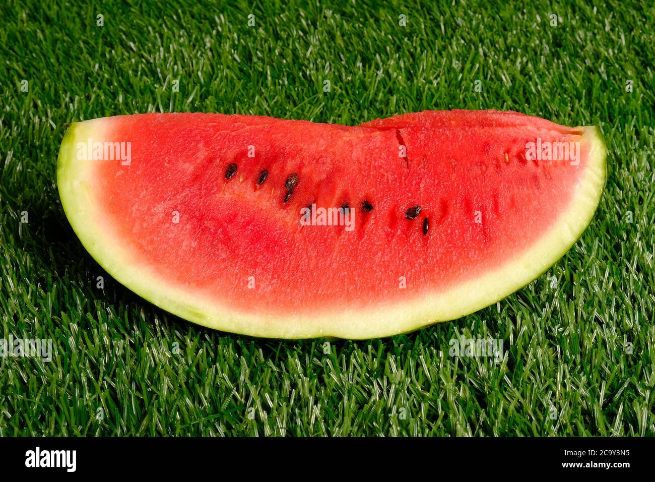 Ein Stück reife saftige Wassermelone liegt auf grünem Gras close-up, Picknick. Stockfoto