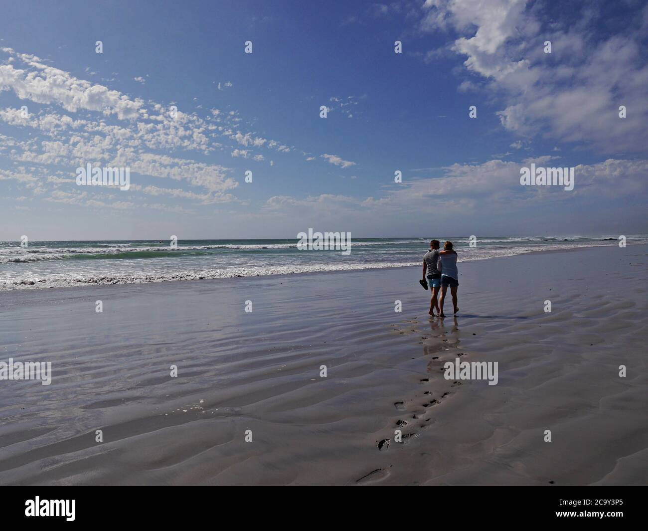 Junges Paar in Sommerkleidung auf menschenleeren, weißen Sandstrand zu Fuß Stockfoto