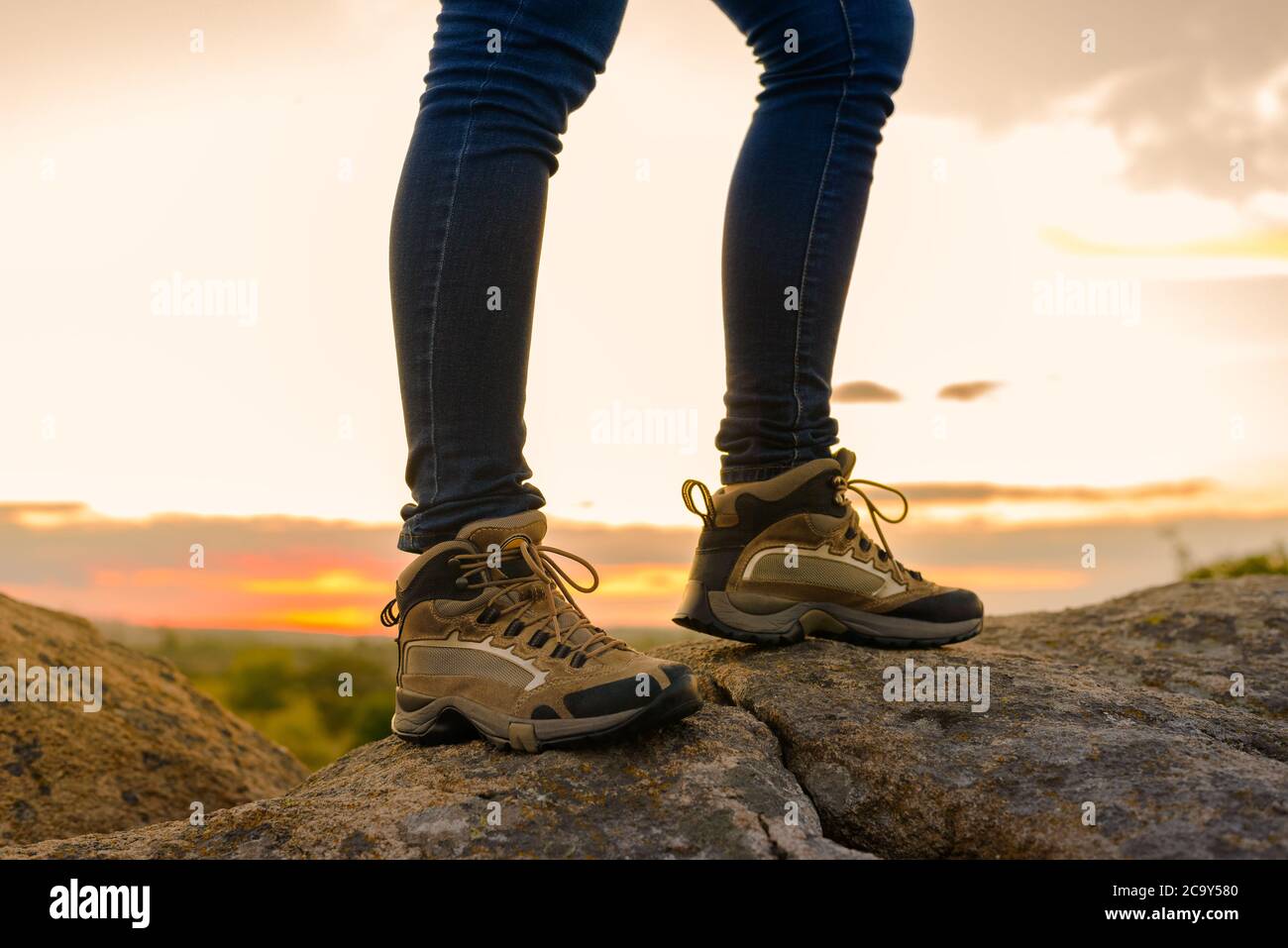 Die Beine des Wanderers auf dem Rocky Trail bei Sonnenuntergang im Sommer. Reise- und Abenteuerkonzept. Stockfoto