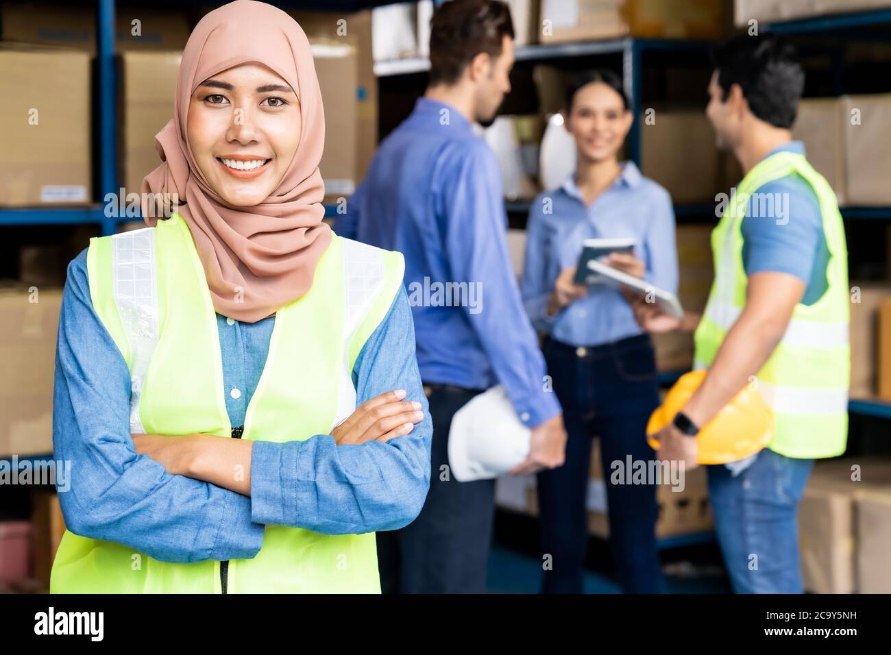 Portrait of Islam muslimische Lagerarbeiterin kreuzte den Arm mit ihren Kollegen, die sich im Lager-Distributionszentrum treffen. Für Geschäftsreisende wa Stockfoto