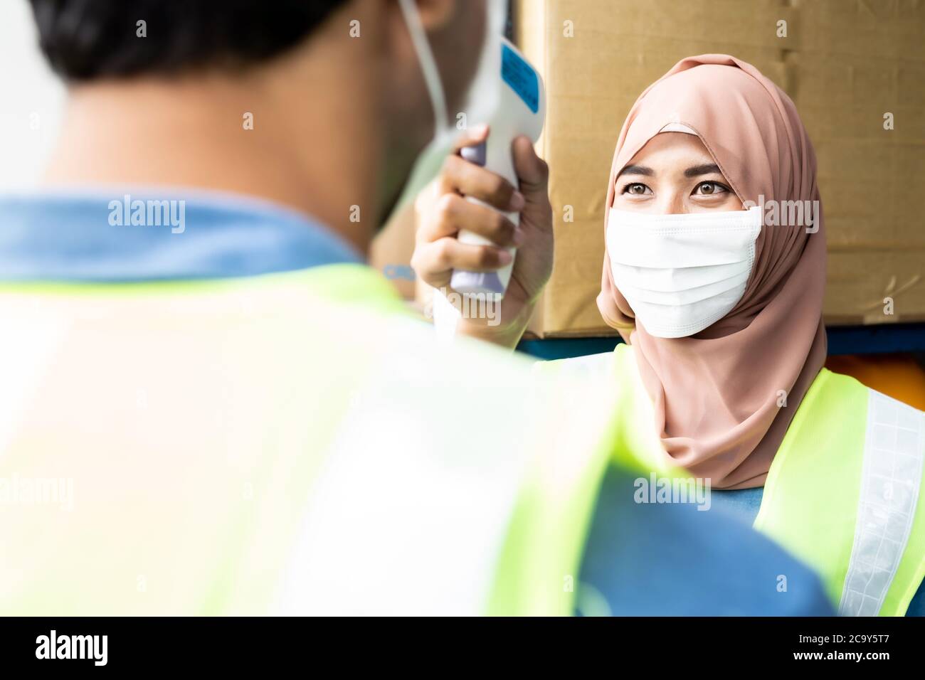 Islam asiatische Lagerarbeiter Temperatur zu Arbeiter, bevor sie in der Fabrik nach der Wiedereröffnung nach Stadt Sperre von COVID-19 Coronavirus Pandem Stockfoto