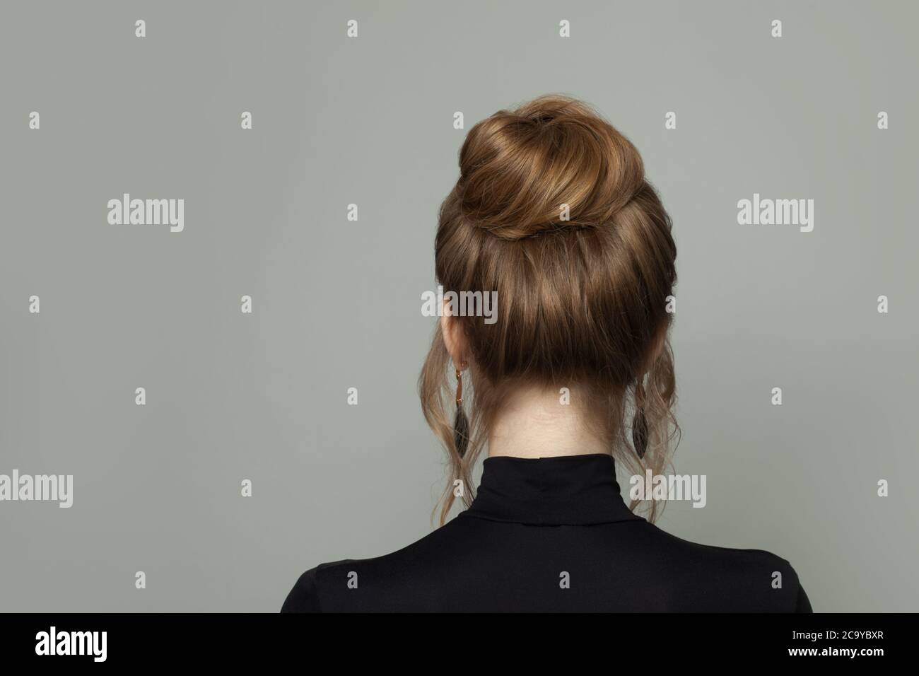 Schöne Frau zurück mit updo Frisur auf grauem Hintergrund Stockfoto