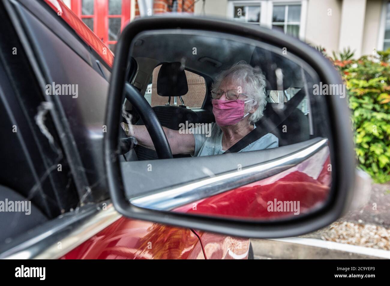 Ältere Frau in den 80ern saß auf dem Fahrersitz ihres Autos, England, Vereinigtes Königreich Stockfoto