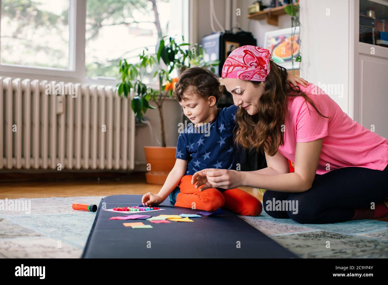 Junge Mutter und Kind machen Papier Handwerk zusammen zu Hause Stockfoto