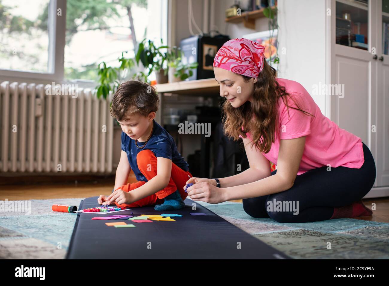 Junge Mutter und Kind machen Papier Handwerk zusammen zu Hause Stockfoto