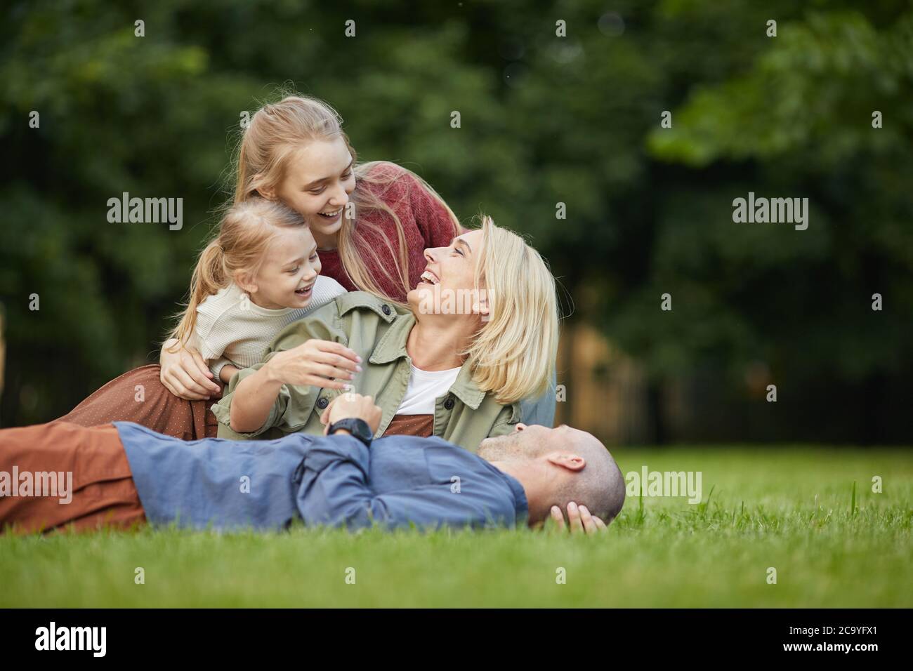 Porträt der glücklichen modernen Familie auf grünem Gras im Park liegen, während Spaß zusammen im Freien, kopieren Raum Stockfoto