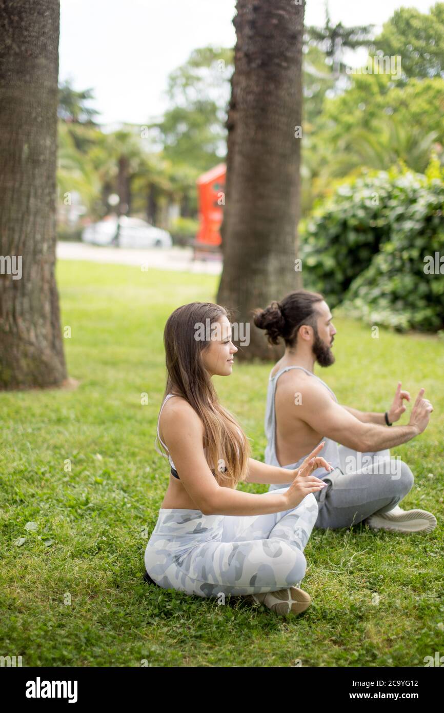 Professionelle yoga Trainer und seine Schülerin führen Ihre outdoor Training in einem grünen Stadtpark. Das Konzept einer gesunden Lebensweise. Stockfoto