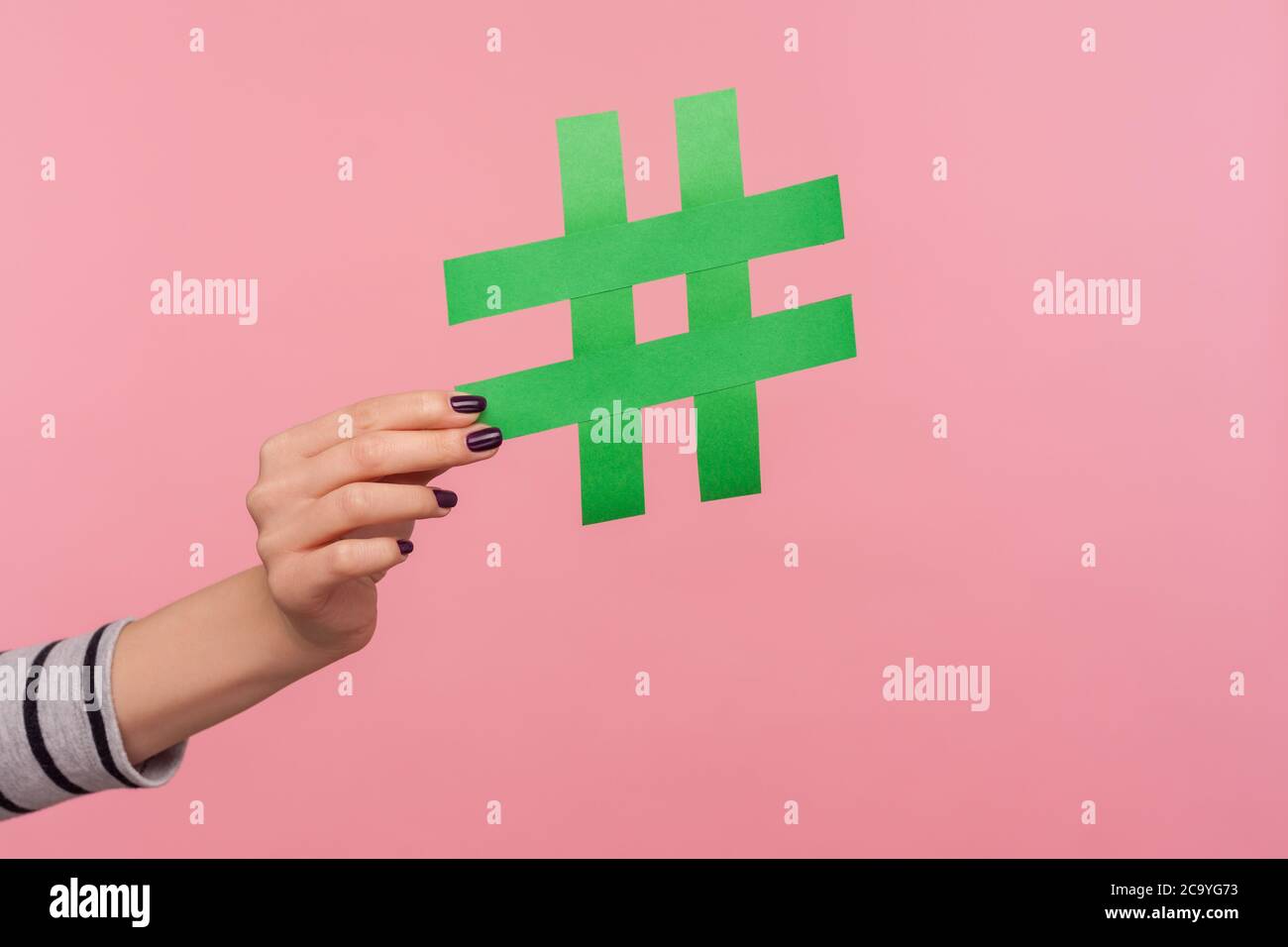 Nahaufnahme Hand mit großen grünen Papier Hashtag-Zeichen, zeigt Hash-Symbol als Empfehlung, um Internet-Trends, viralen Blog-Thema, berühmte Nachricht folgen. Stockfoto