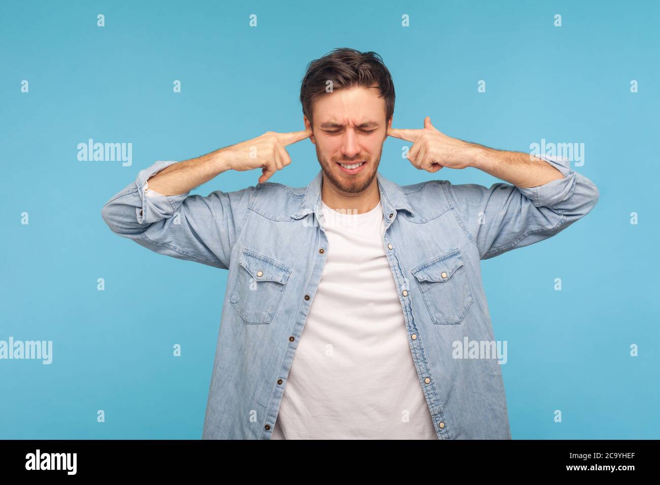 Wollen Sie nicht zuhören! Porträt des Mannes in Arbeiter-Denim-Shirt Ohren schließen und grimacing unzufrieden, irritiert durch Lärm, schwer zu hören ärgerlich soun Stockfoto