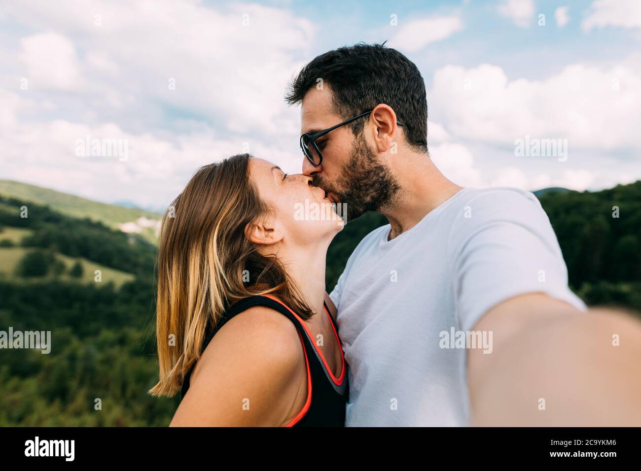 Junges Paar nimmt ein Selfie beim Küssen in den Bergen Stockfoto