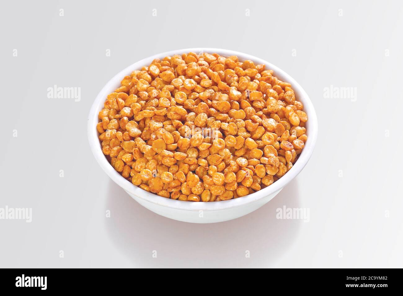 Gebraten und würzig Chana Dal ist ein sehr beliebter Gujarati Snack, weiße Schüssel auf weißem Hintergrund, Beutel Verpackung gemeinsame Straße Snack aus Indien, selektiv Stockfoto