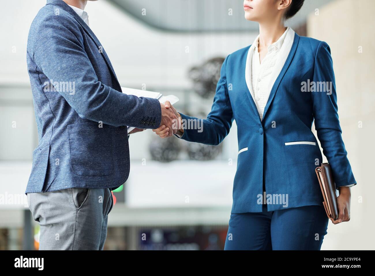 Beschnittenes Bild von ernsthaften jungen Unternehmerinnen und Unternehmerinnen, die die Hände schütteln Stockfoto