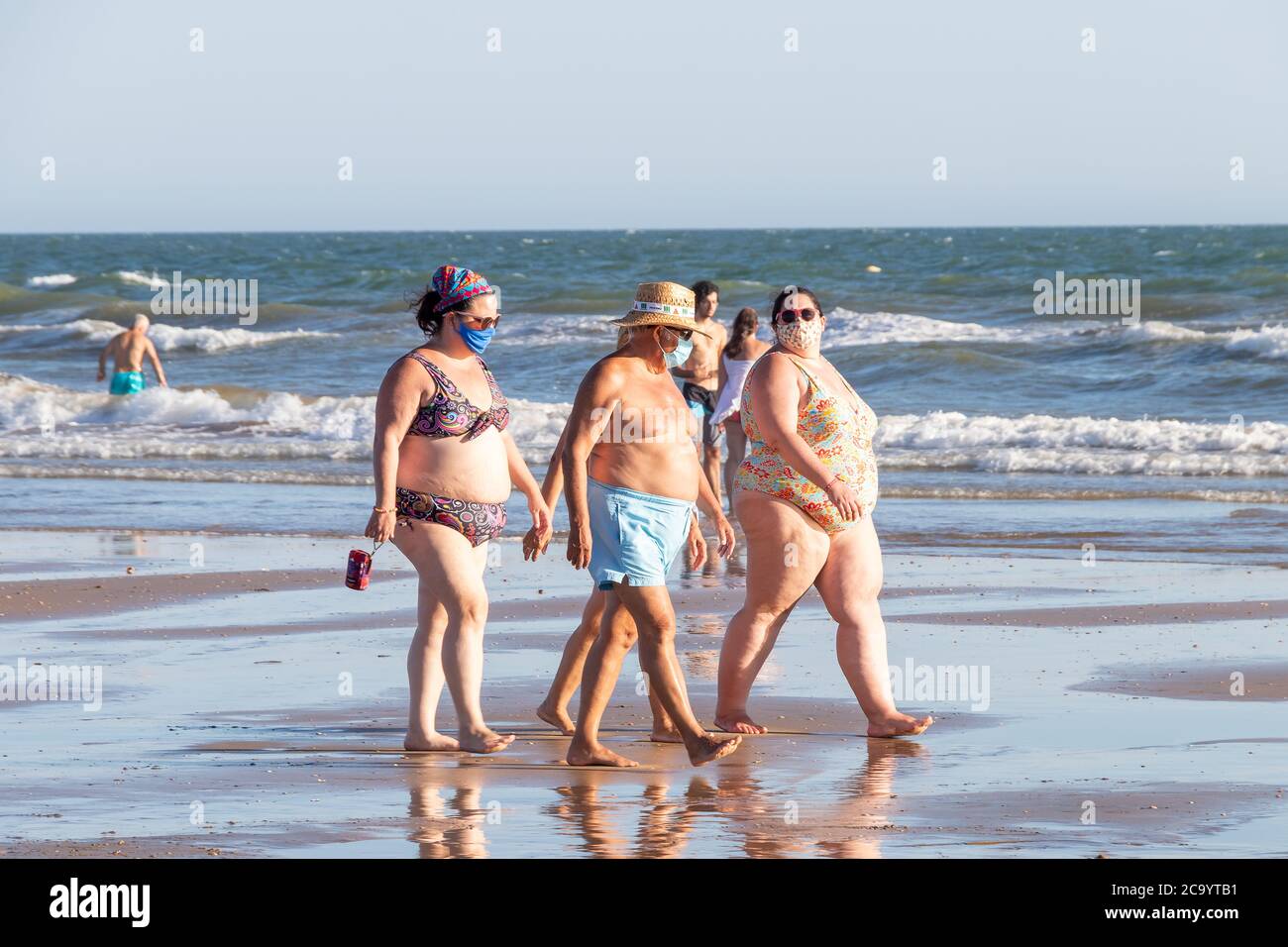 Punta Umbria, Huelva, Spanien - 2. August 2020: Menschen mit Übergewicht beim Strandspaziergängen mit schützenden oder medizinischen Gesichtsmasken. Neue Normalität in Spai Stockfoto