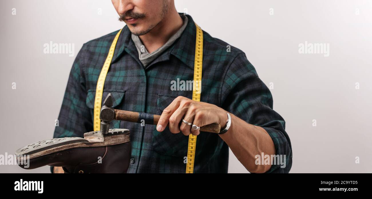 7/8-Ansicht von unkenntlich Schuster mit Maßband und Hammer, handgefertigte Schuhe im Studio Handwerk Stockfoto