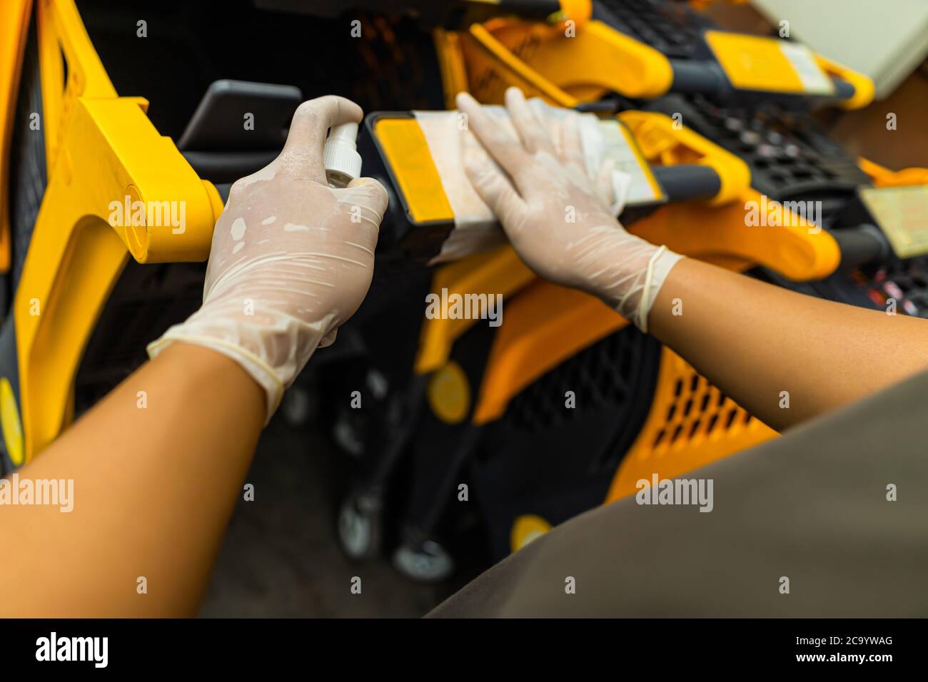 Hände von Menschen mit Sprühen Alkohol antiseptisch, Desinfektionsspray, Reinigung auf Warenkorb, Trolley Griff, Schutz während Coronavirus Pandemie, C Stockfoto