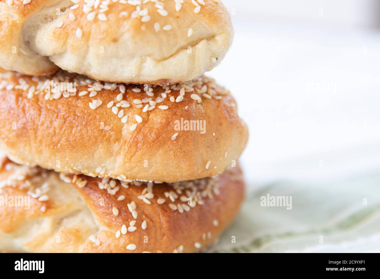 Hausgemachte Bagels mit Sesamsamen auf Stoff mit High-Key-Hintergrund und negativem Platz zum Kopieren gestapelt Stockfoto