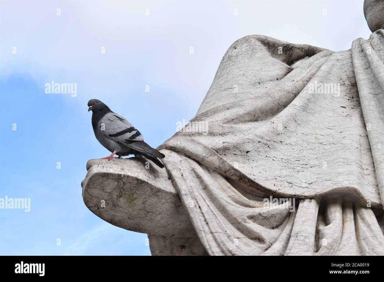 Eine Taube sitzt am Fuß einer riesigen Marmorstatue in Lissabon, Portugal Stockfoto