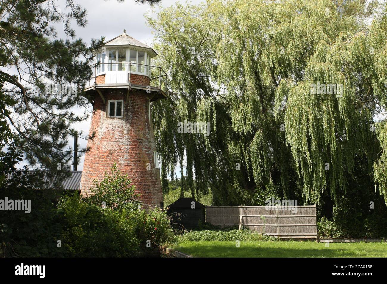 Alte Windmühle in Unterkunft umgewandelt, neben Weidenbaum, Norfolk Broads, England Stockfoto