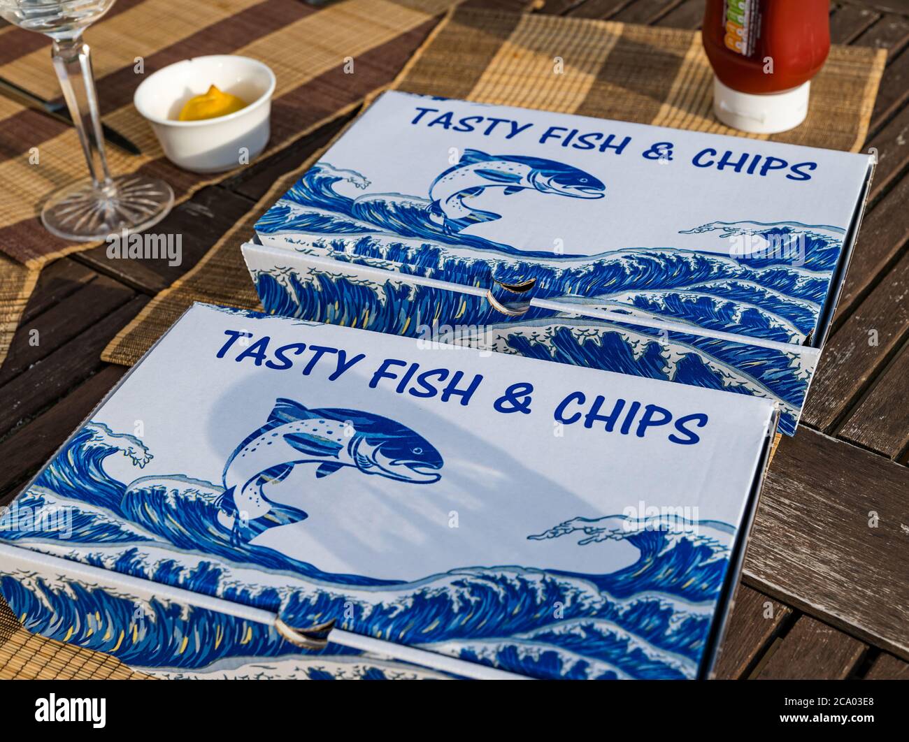 Schellfisch und Pommes oder Fischessen in Takeaway Boxen bei Sommersonne auf Terrasse Tisch, Schottland, Großbritannien Stockfoto