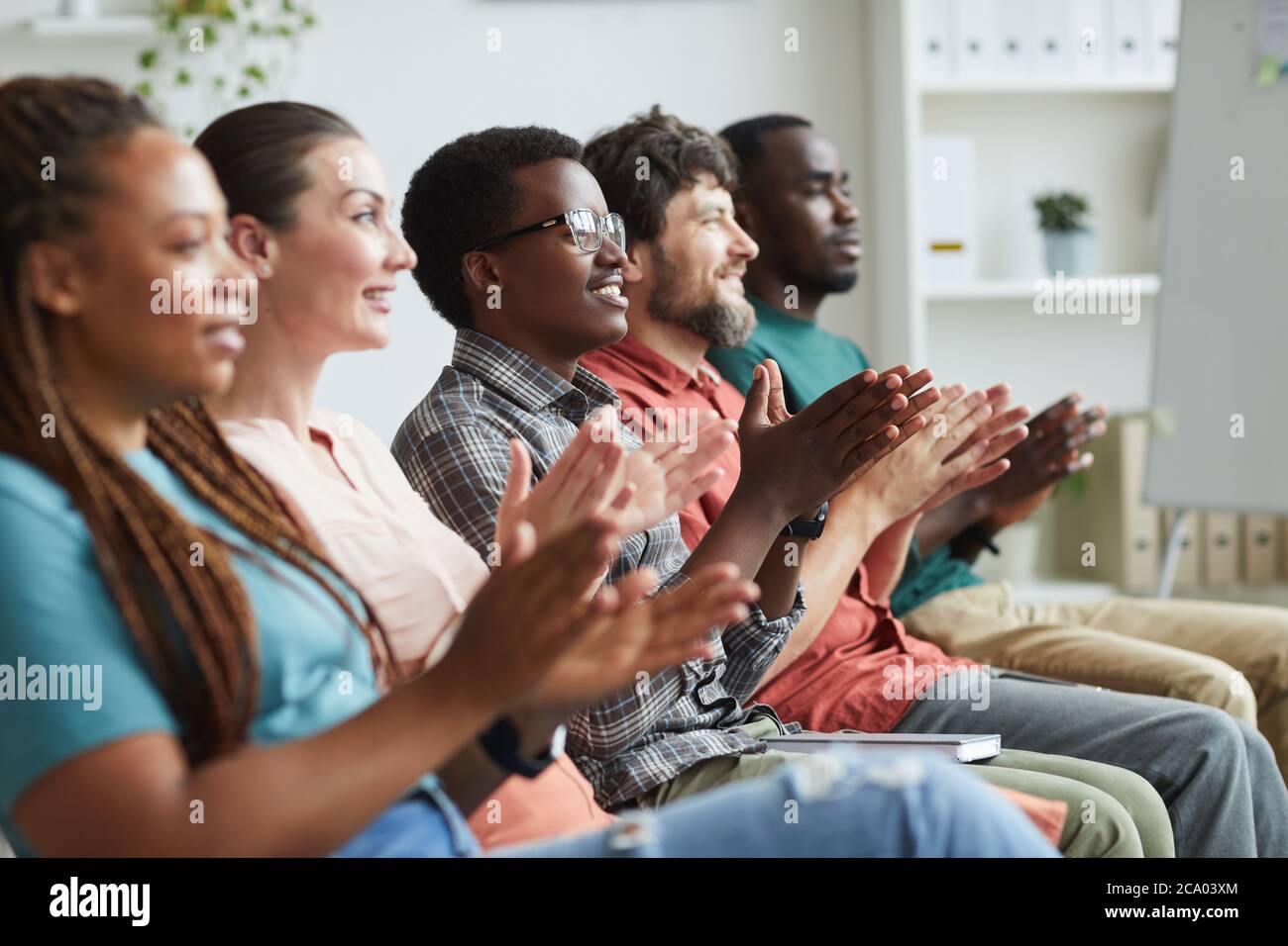 Seitenansicht Porträt einer multiethnischen Gruppe von Menschen applaudieren, während in Reihe sitzen im Publikum oder Konferenzraum, kopieren Raum Stockfoto
