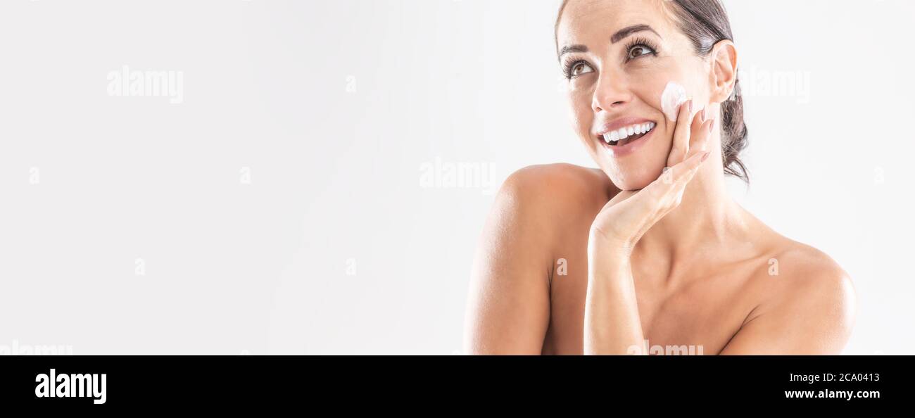 Schöne junge Frau Anwendung Creme auf ihr Gesicht isoliert auf weiß. Hautpflege Spa Wellness und Kosmetik-Konzept. Stockfoto