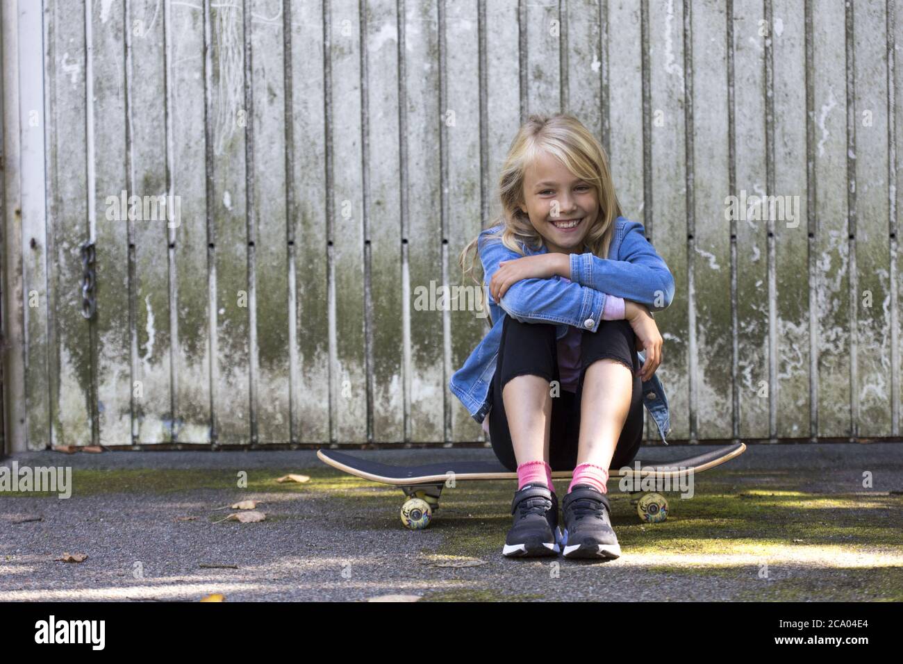 Mädchen (10) sitzend auf Skateboard, Kiel, Schleswig-Holstein, Deutschland Stockfoto