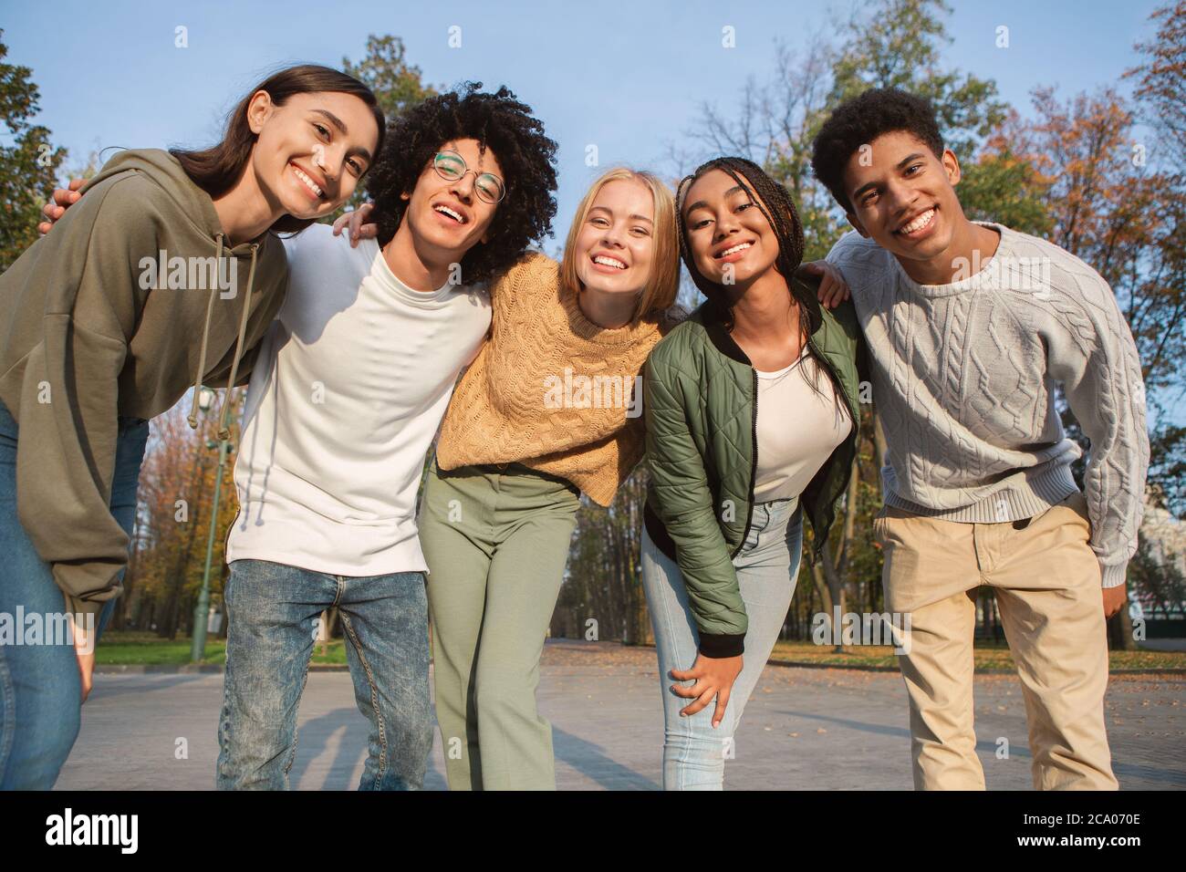 Lustige multiethnische Teenager lächeln vor der Kamera im Freien Stockfoto