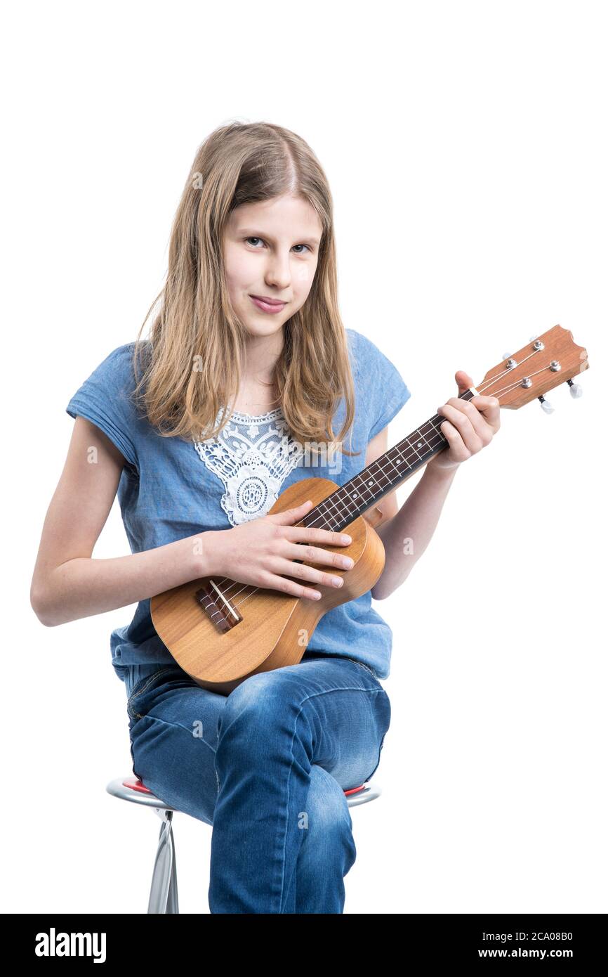 Teenager, blonde Mädchen in blauem T-Shirt sitzt und spielt Musik auf Ukulele Instrument. Stockfoto