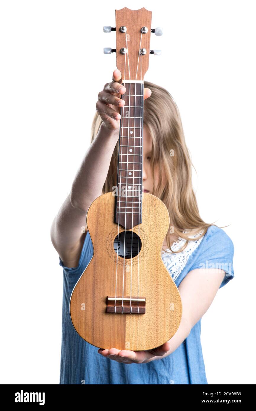 Teenager, blonde Mädchen in blauem T-Shirt hält hellbraune Ukulele Instrument. Stockfoto