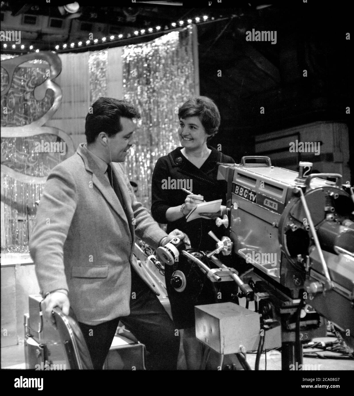 John Hughes Produzent der BBC-Musikfernsehsendung Top Der Pops steht neben einem altmodischen Fernseher reden Kamera im 1960s Stockfoto