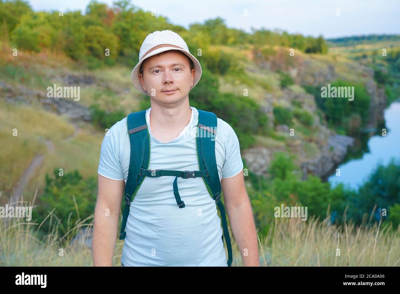 Ein Typ im T-Shirt und mit Rucksack reist durch die Berge des Canyons und schaut auf den Sonnenuntergang Stockfoto