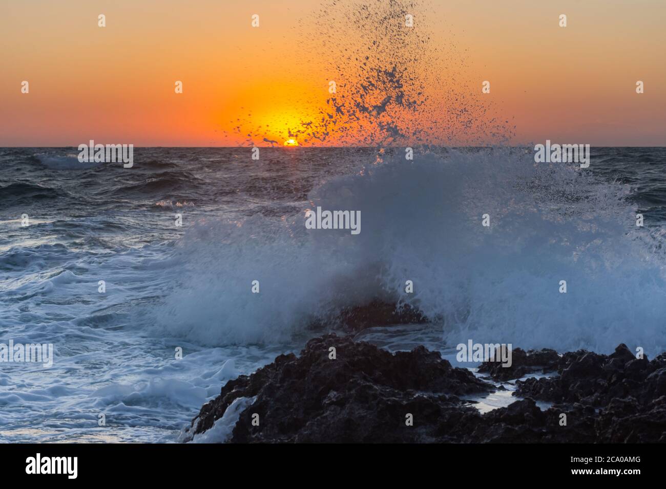 Sonnenuntergang und Sturm auf dem Meer. Große Wellen vor dem Hintergrund der untergehenden Sonne. Sommersturm auf dem Schwarzen Meer. Wunderschöne Meeresbrause auf den Felsen. Stockfoto