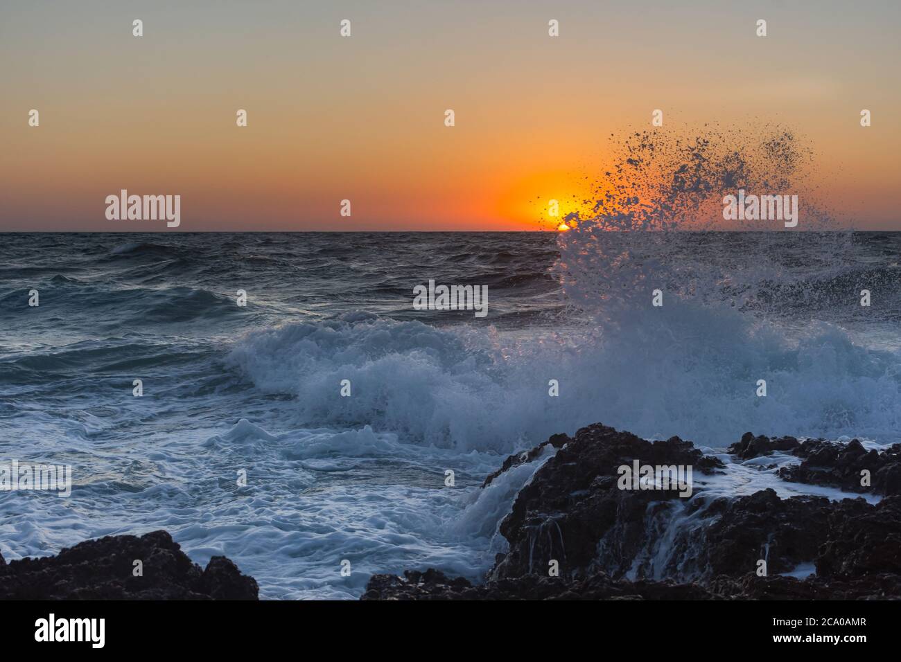 Sonnenuntergang und Sturm auf dem Meer. Große Wellen vor dem Hintergrund der untergehenden Sonne. Sommersturm auf dem Schwarzen Meer. Wunderschöne Meeresbrause auf den Felsen. Stockfoto