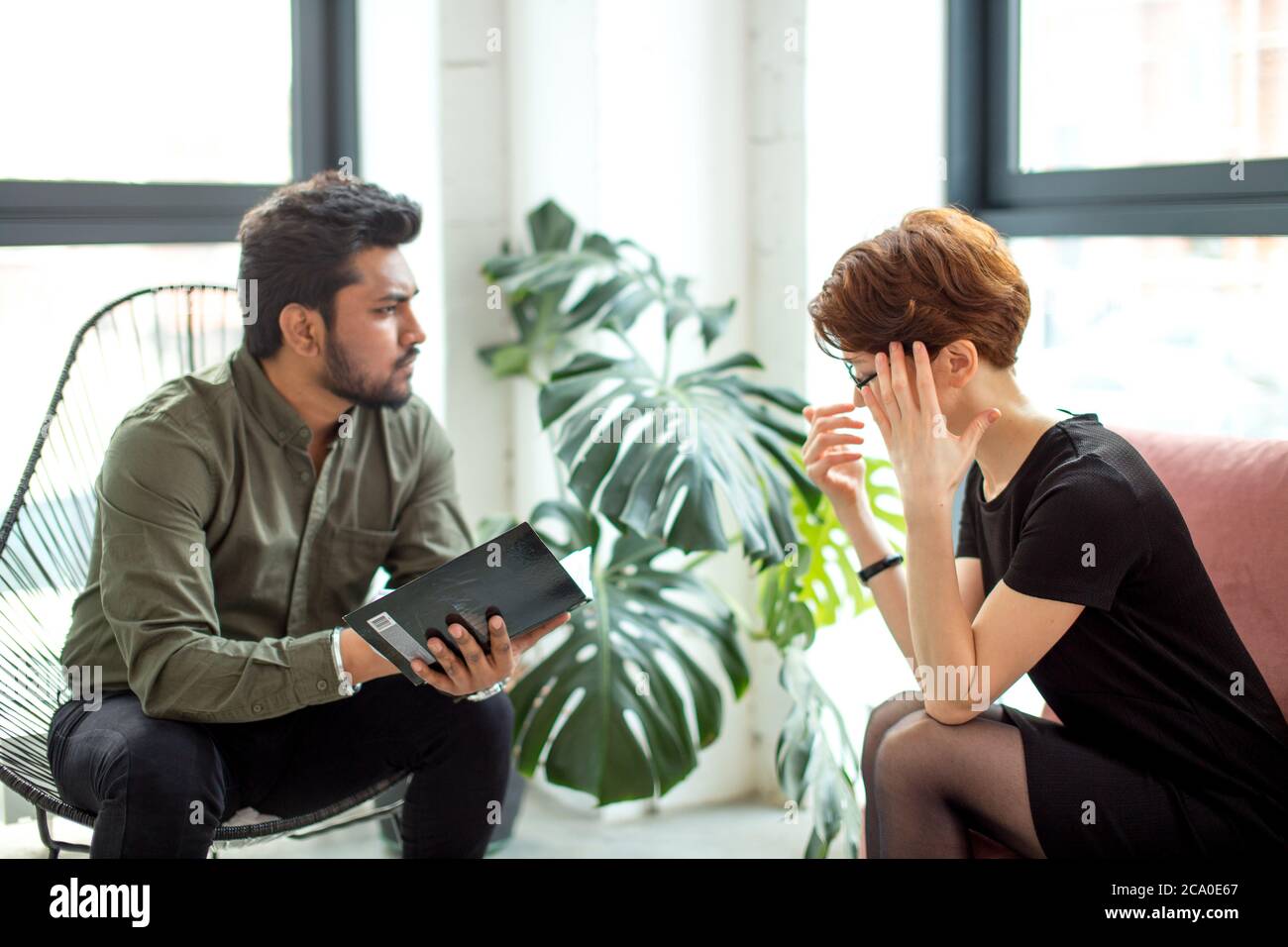 Junge Frau besucht indischen Psychologen für unerwiderte Liebe. Weibliche Klientin diskutieren mit männlichen Arzt, während er Notizen zu schreiben Stockfoto