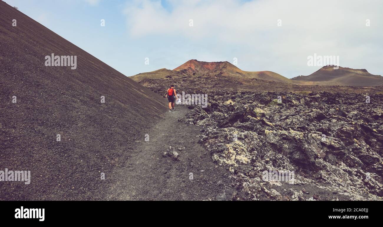 Wanderweg auf dem Vulkan Caldera de la Rilla im Naturpark Los Volcanes, mit einem Wanderer und Montana de Santa Catalina in der Ferne. Stockfoto