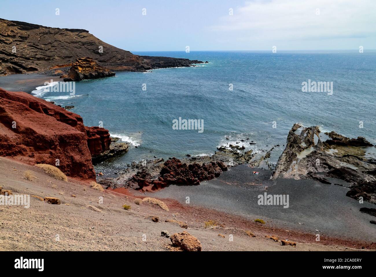 Felsige vulkanische Küste mit roter Erde und schwarzem Sand am Atlantik in El Golfo, Lanzarote, Kanarische Inseln, Spanien. Stockfoto