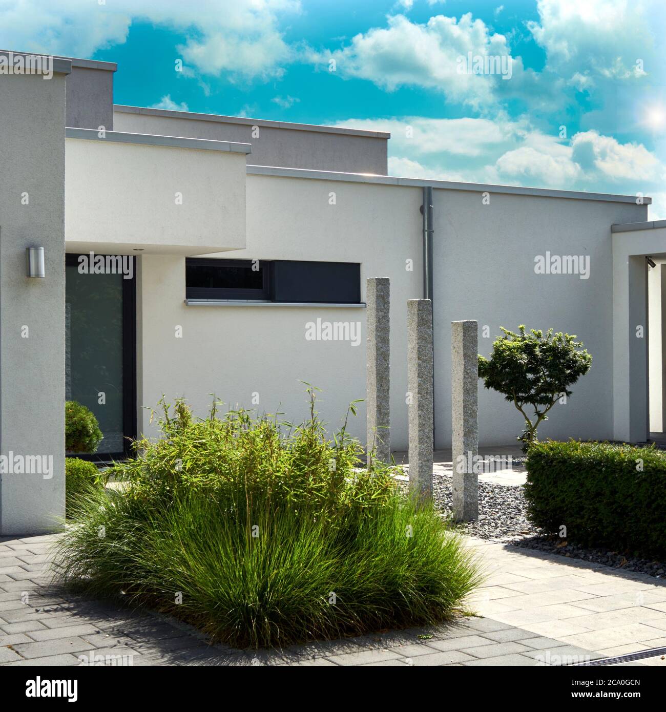 Vorgarten eines modernen minimalistischen Haus mit Steinsäulen und einem Rasen in einem Kiesbett, Blick vom öffentlichen Boden Stockfoto