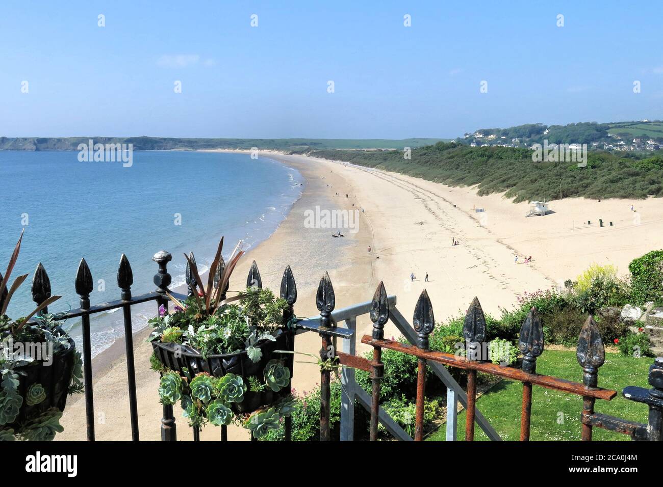 Urlauber tupfen den breiten Sand von South Beach in Tenby, Wales Stockfoto