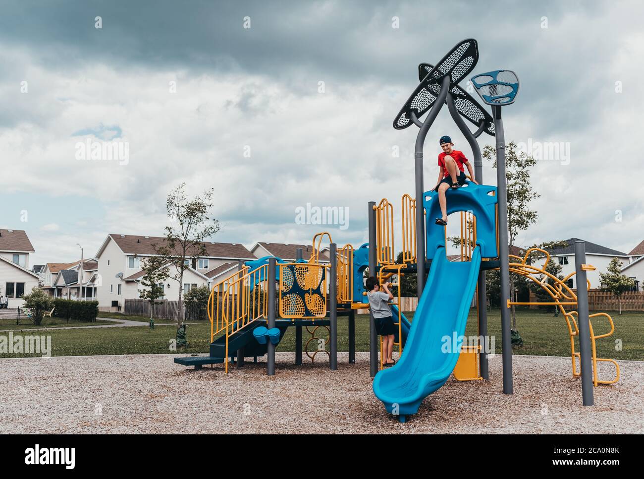 Jungen spielen auf einer Spielstruktur auf einem Spielplatz am bewölkten Sommertag. Stockfoto