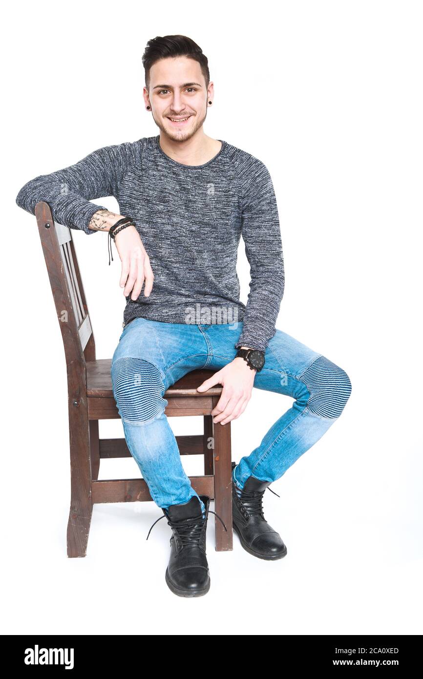 Junger Mann lächelt auf einem Stuhl Stockfoto
