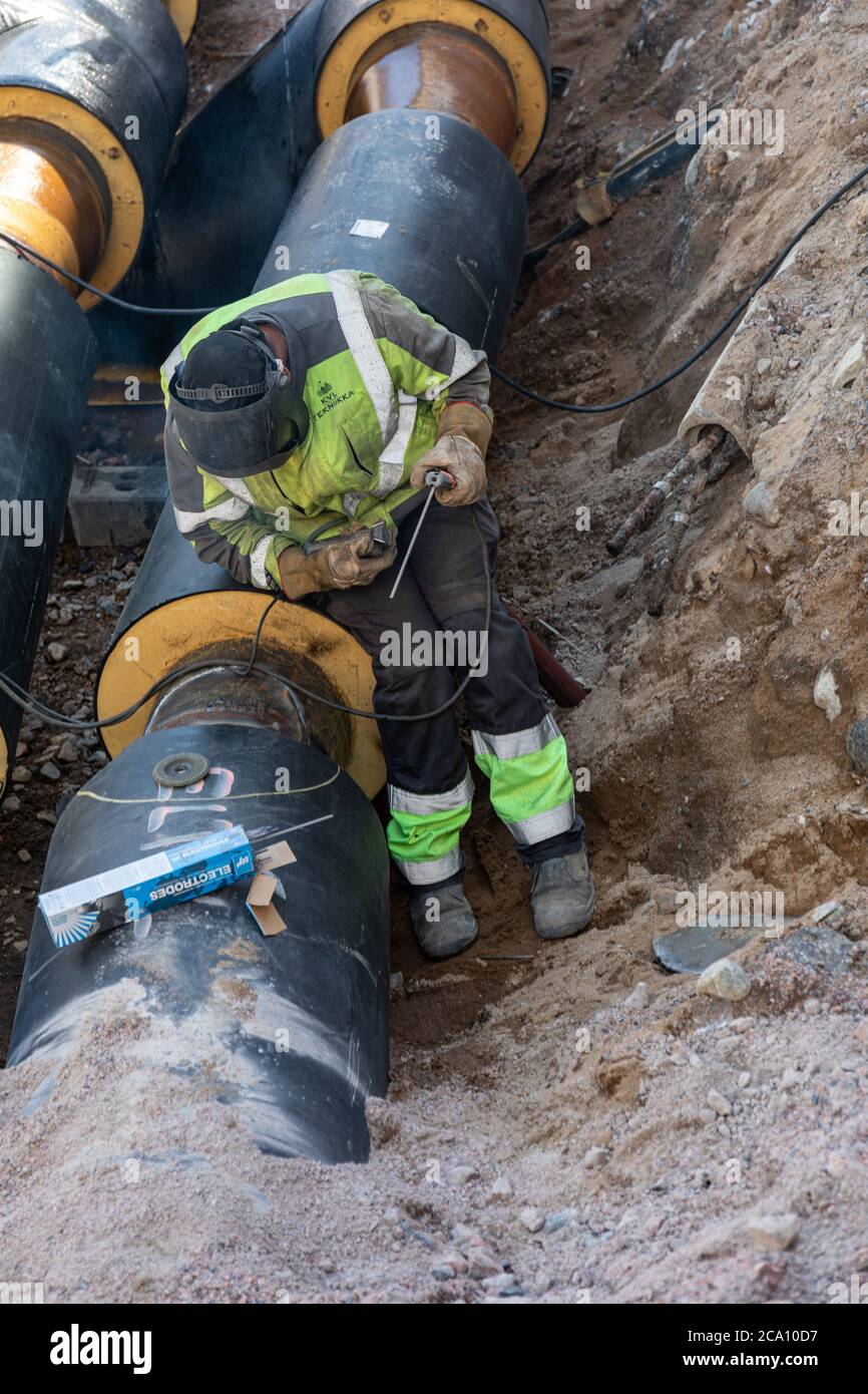 Schweißarbeiter, der die Schweißverbindung an einem isolierten Fernwärmerohr überprüft Stockfoto