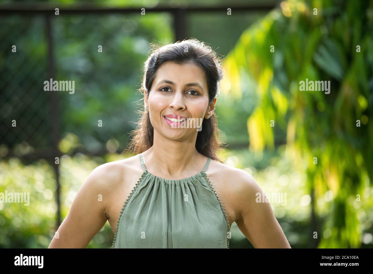 Porträt einer glücklichen Frau im Park, die die Kamera anschaut Stockfoto