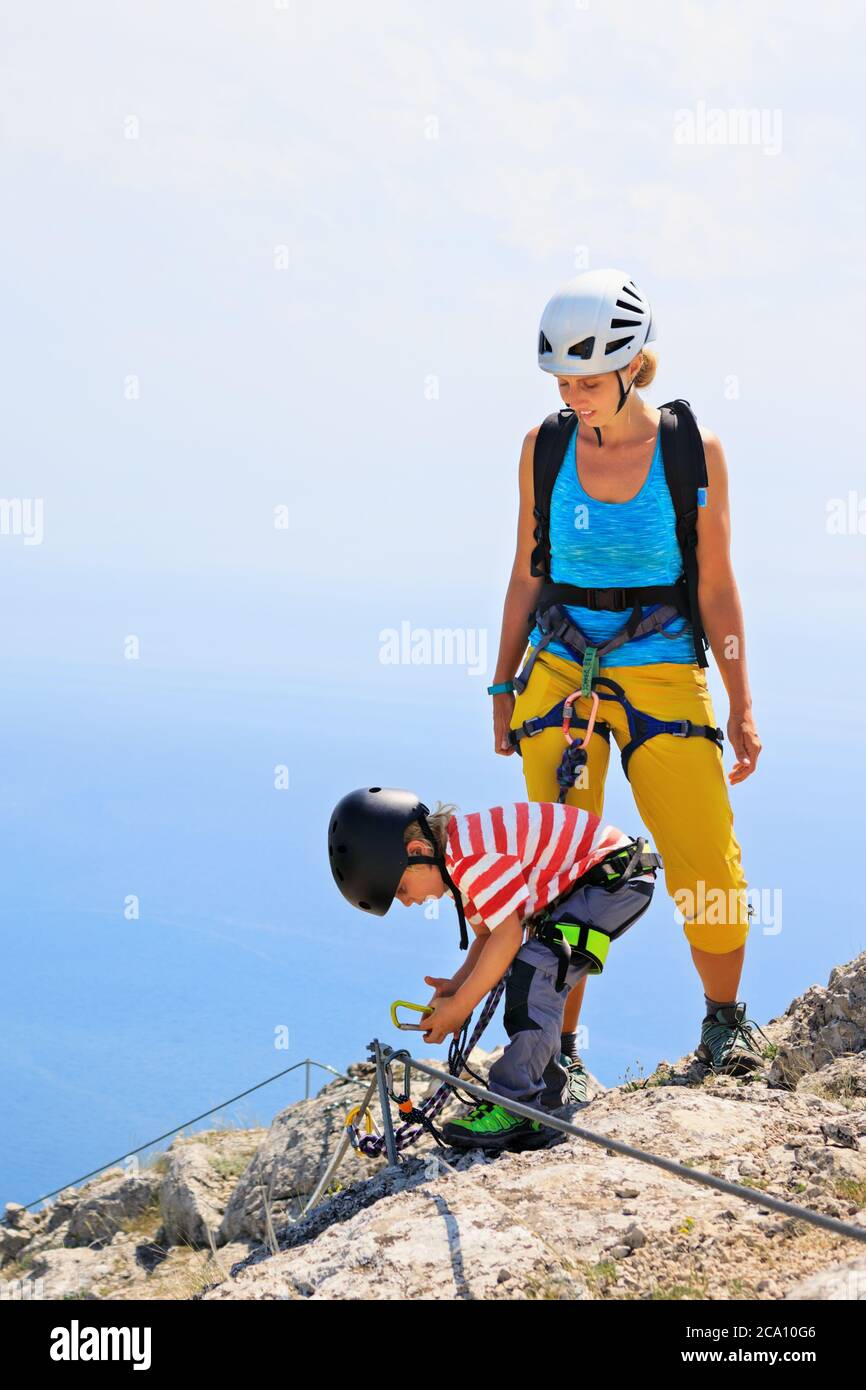 Junge Mutter, Kind in Sicherheitsausrüstung Aufstieg zum Gipfel mit Klettersteig Anfängerroute. Familienreise Abenteuer. Wanderaktivitäten für Kinder. Stockfoto
