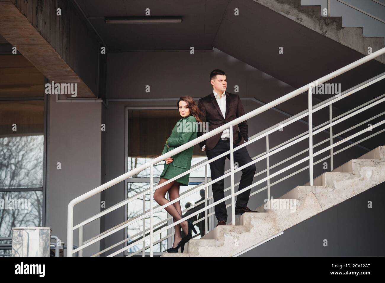 Attraktives junges Paar, das an der Treppe eines Gebäudes steht und sich die verschiedenen Richtungen anschaut Stockfoto