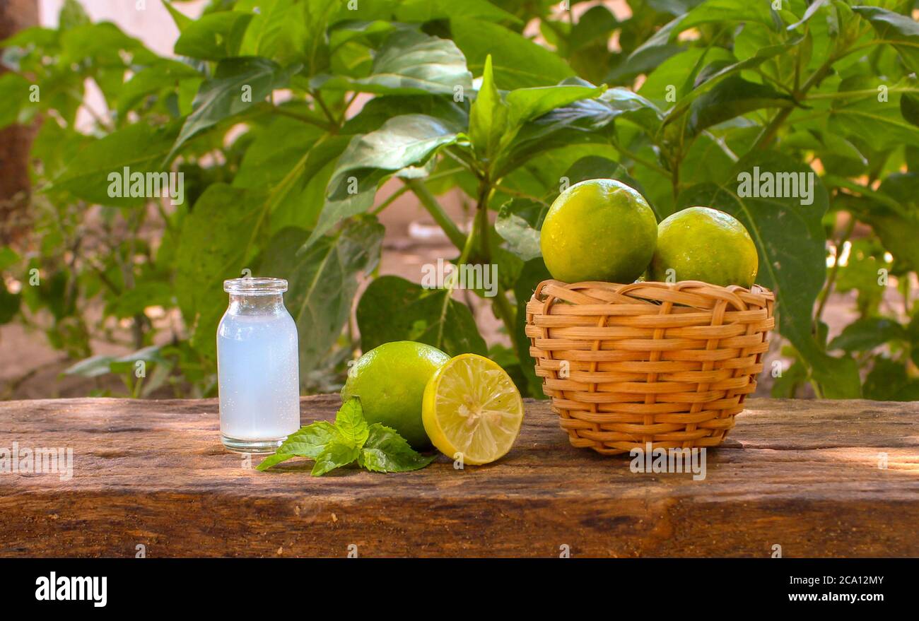 Ein Korb voller Zitronen, halb geschnitten Zitrone und Zitronensaft in einem Glas Nahaufnahme Stockfoto