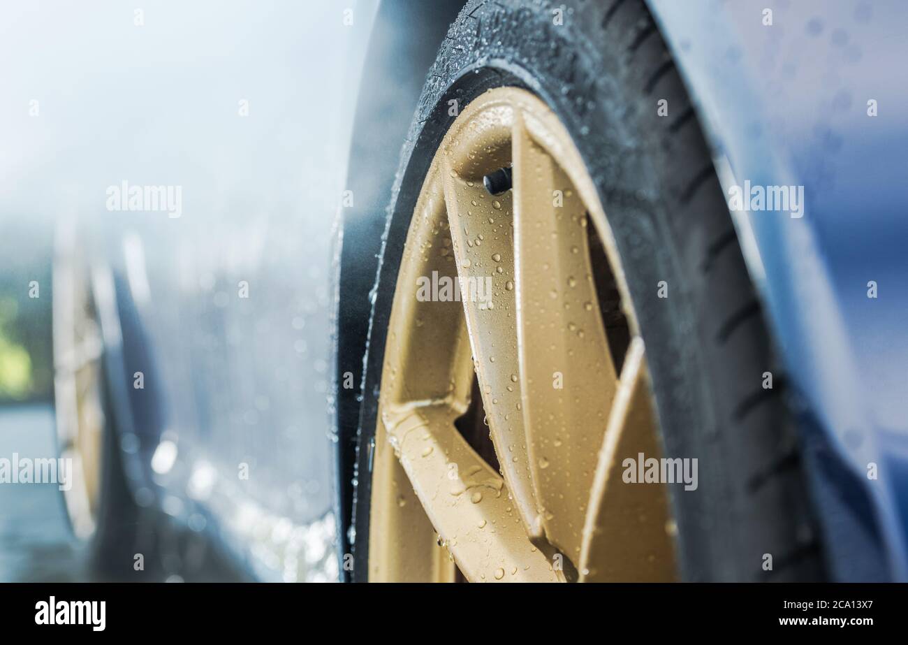 Reinigung exotische Auto in Auto Wash. Goldene Legierung Rad durch Wassertropfen abgedeckt Close Up. Thema Automobil und Transport. Stockfoto