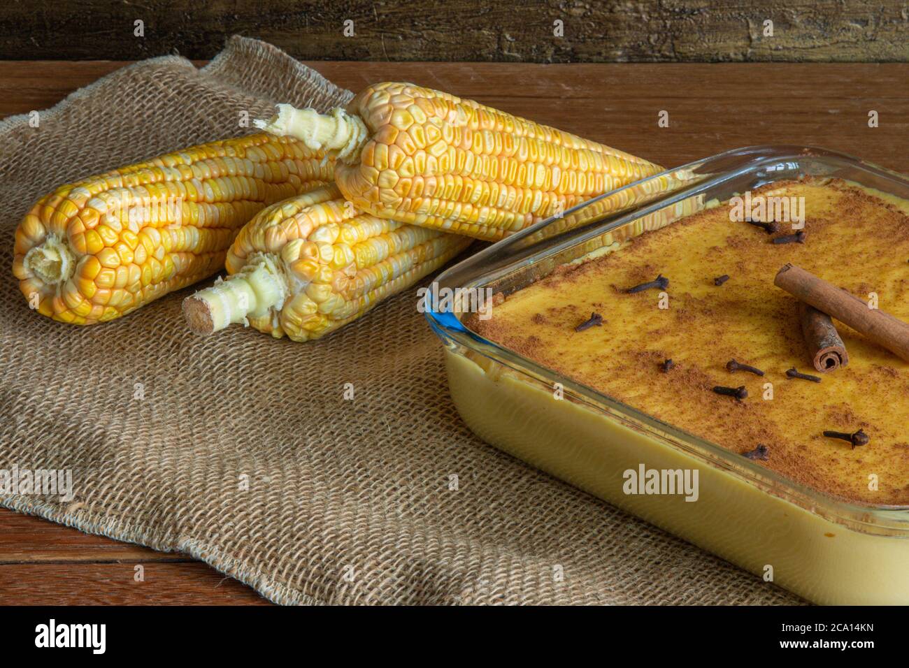 Canjica Curau. Typische brasilianische Junina Party Süßigkeiten. Maiskolben. Rustikaler Holzhintergrund. Brasilianisches Dessert Stockfoto