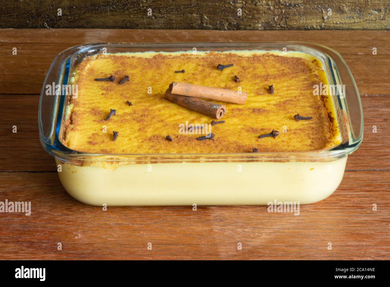 Canjica Curau. Typische brasilianische Junina Party Süßigkeiten. Rustikaler Holzhintergrund. Brasilianisches Dessert Stockfoto